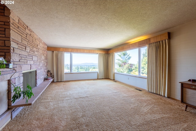 unfurnished living room featuring plenty of natural light, a fireplace, and carpet