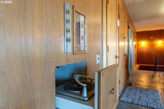 hallway featuring wood walls, a textured ceiling, and tile patterned flooring