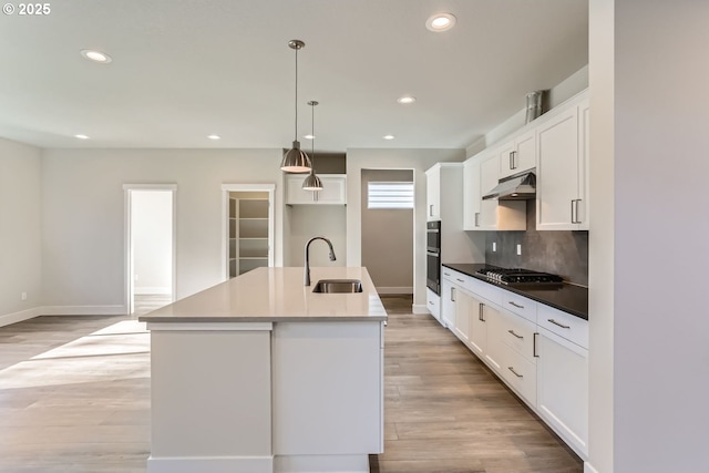 kitchen with sink, an island with sink, white cabinetry, and hanging light fixtures