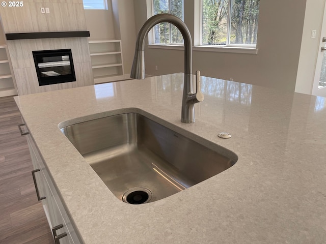 details featuring sink, light stone countertops, a kitchen breakfast bar, and dark hardwood / wood-style flooring