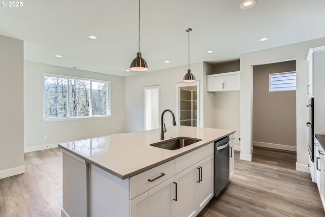 kitchen featuring a center island with sink, sink, pendant lighting, stainless steel appliances, and white cabinets