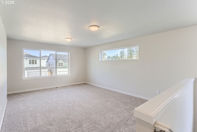 carpeted empty room featuring a textured ceiling