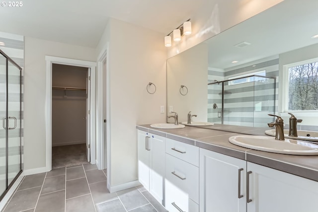 bathroom featuring tile patterned floors, a shower with shower door, and vanity