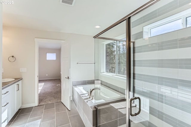 bathroom featuring plus walk in shower, vanity, and tile patterned flooring