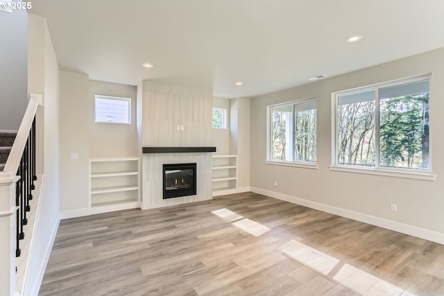 unfurnished living room with plenty of natural light, light hardwood / wood-style flooring, and a fireplace