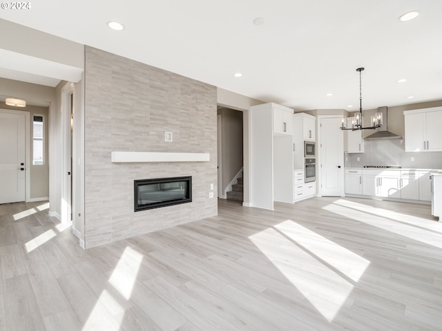 unfurnished living room with a notable chandelier, light hardwood / wood-style floors, and a fireplace