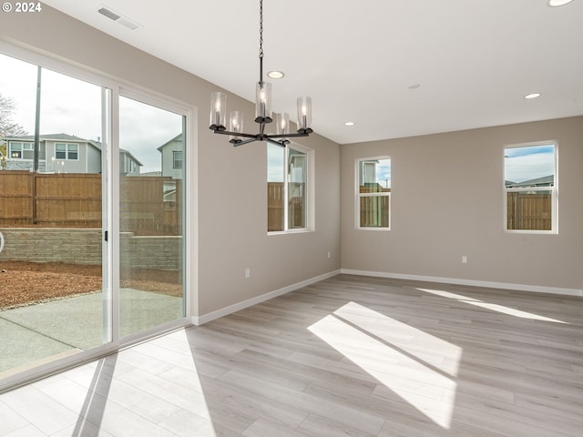 unfurnished dining area featuring light wood-type flooring and an inviting chandelier