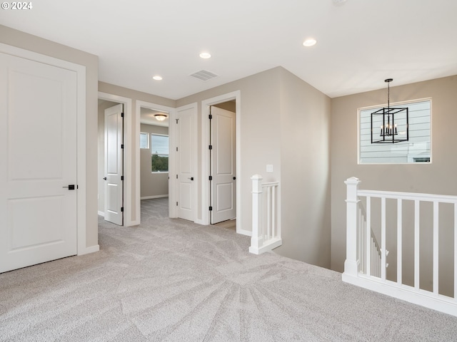 corridor featuring light carpet and an inviting chandelier