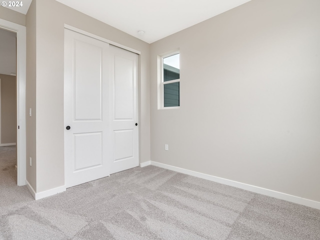 unfurnished bedroom featuring light colored carpet and a closet