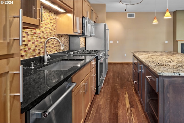 kitchen featuring sink, a center island, light stone counters, dark hardwood / wood-style floors, and appliances with stainless steel finishes