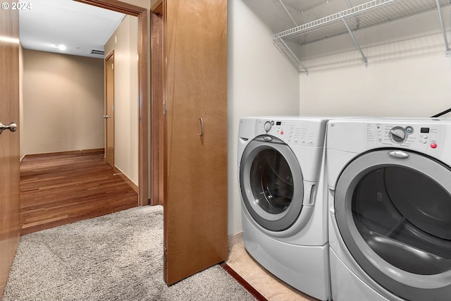 laundry area with independent washer and dryer and light hardwood / wood-style flooring