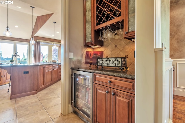 bar featuring wine cooler, dark stone countertops, pendant lighting, and light tile patterned floors