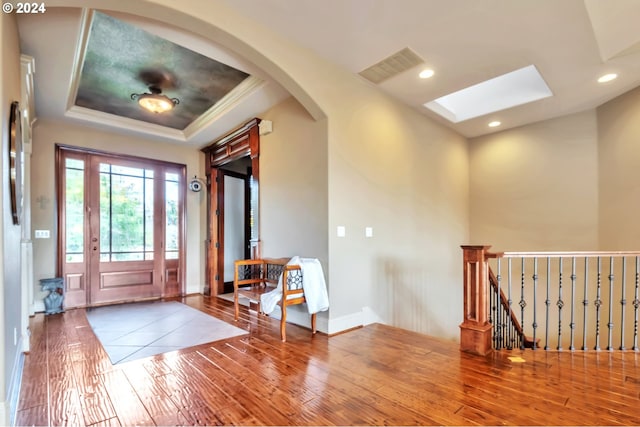 entryway with crown molding, a skylight, a tray ceiling, and hardwood / wood-style floors