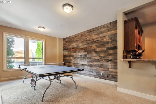 recreation room featuring wood walls and light colored carpet