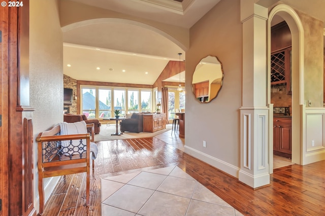 entryway with vaulted ceiling, decorative columns, and light hardwood / wood-style flooring