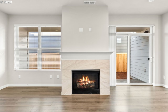 unfurnished living room featuring wood-type flooring and a tiled fireplace