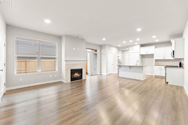 unfurnished living room with sink, a tile fireplace, and light hardwood / wood-style flooring