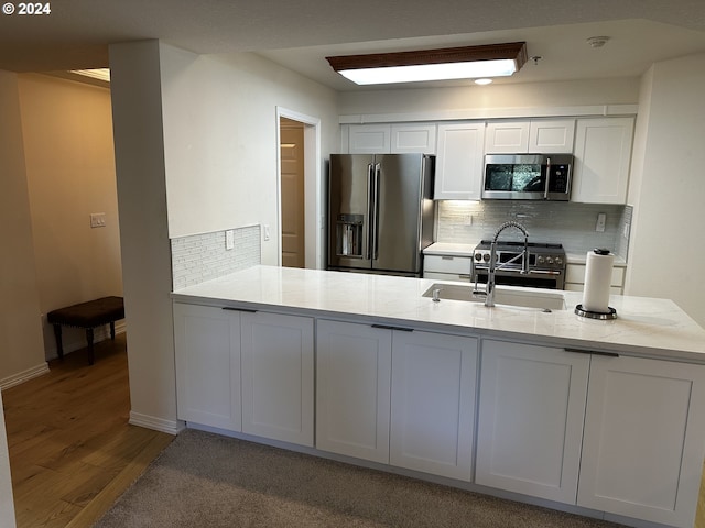 kitchen with decorative backsplash, hardwood / wood-style floors, premium appliances, white cabinets, and sink