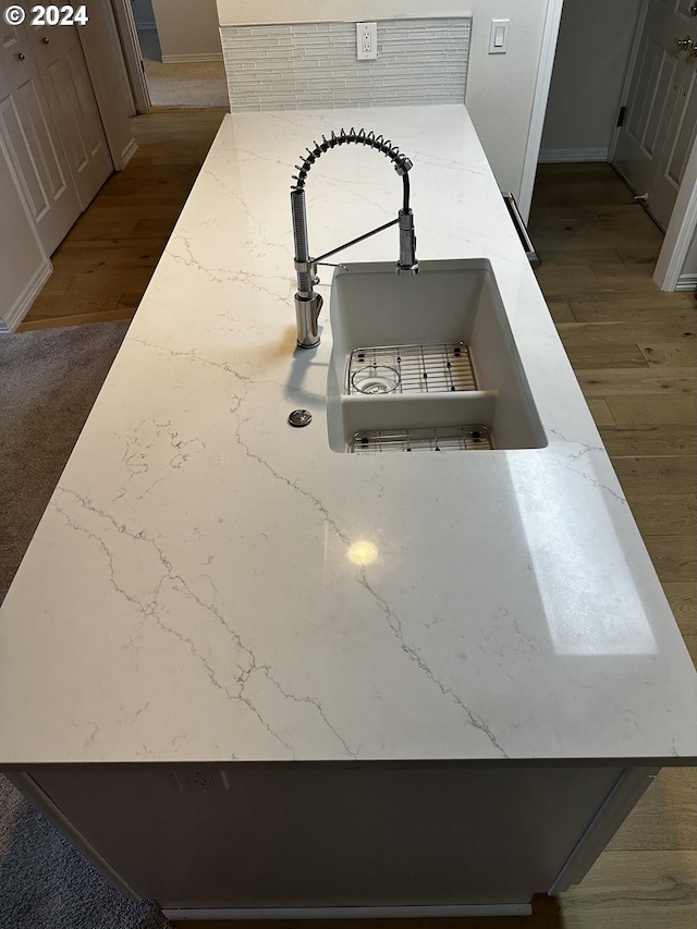 details featuring tasteful backsplash, wood-type flooring, and sink