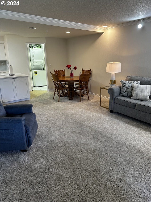 carpeted living room featuring stacked washer / dryer and a textured ceiling