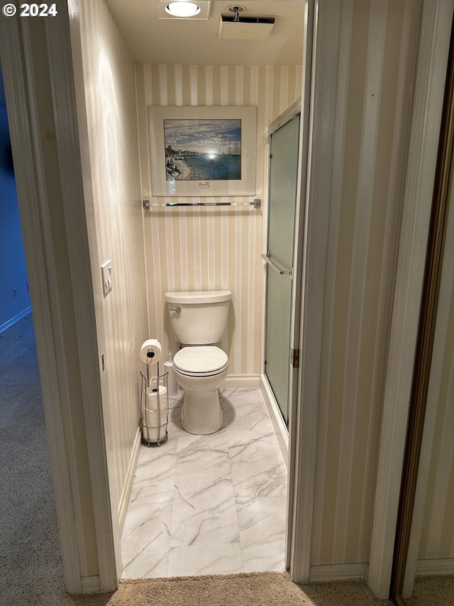 bathroom with a shower with door, toilet, and tile patterned floors