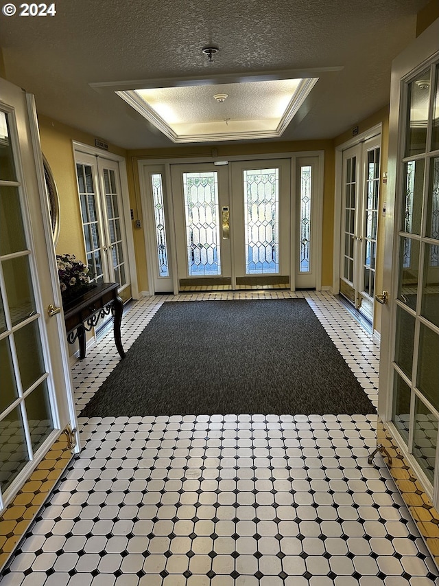 interior space with french doors, a tray ceiling, and crown molding