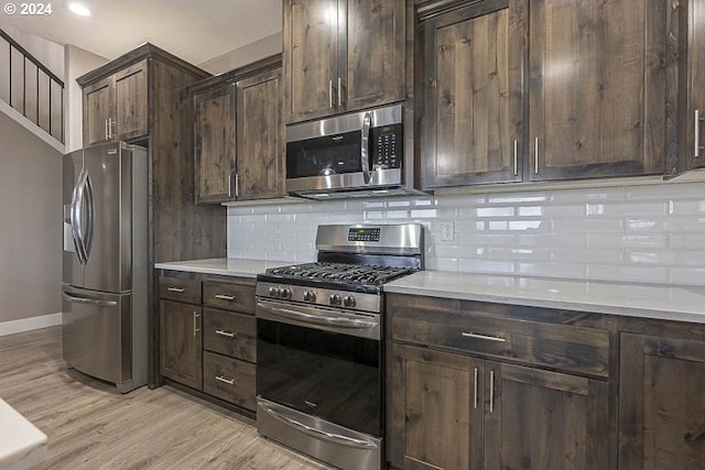 kitchen featuring decorative backsplash, appliances with stainless steel finishes, dark brown cabinetry, and light hardwood / wood-style flooring