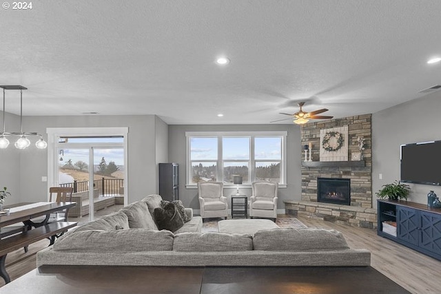 living room featuring a textured ceiling, a healthy amount of sunlight, wood-type flooring, and a fireplace