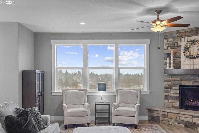 living area with wood-type flooring, a textured ceiling, plenty of natural light, and ceiling fan