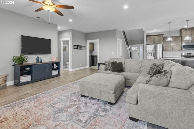 living room with light hardwood / wood-style flooring and ceiling fan