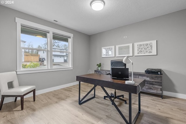 office space featuring light wood-type flooring and a textured ceiling