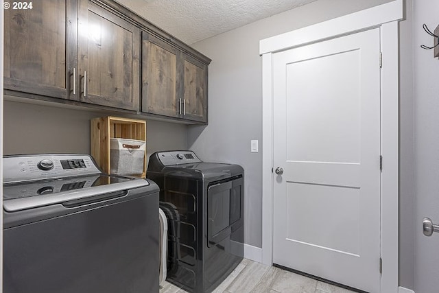 washroom featuring washer and clothes dryer, cabinets, a textured ceiling, and light hardwood / wood-style flooring