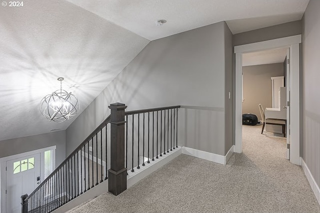 stairway with lofted ceiling, carpet floors, a chandelier, and a textured ceiling