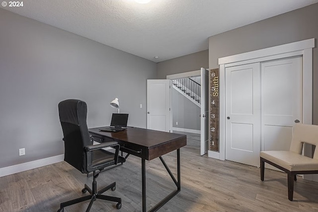 office area with a textured ceiling and light hardwood / wood-style floors