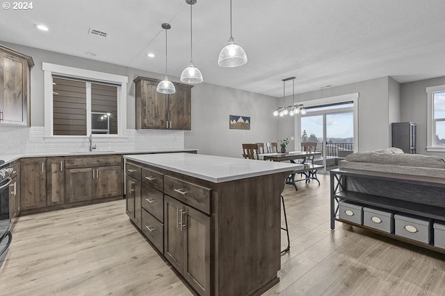 kitchen featuring pendant lighting, a center island, dark brown cabinetry, and backsplash