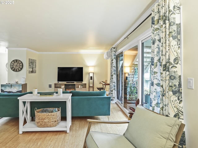 living area featuring light wood-style floors, crown molding, and a glass covered fireplace