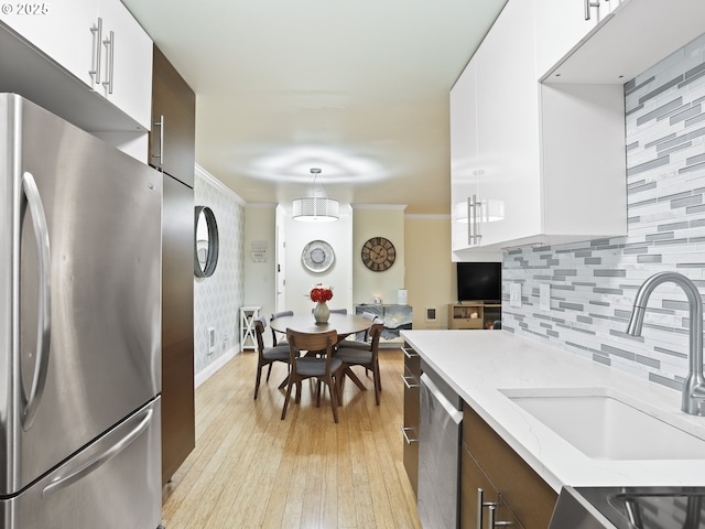 kitchen featuring appliances with stainless steel finishes, white cabinets, a sink, and ornamental molding