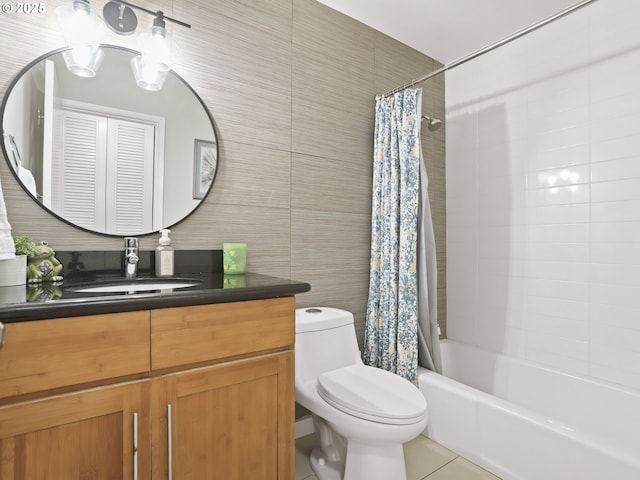 full bathroom with toilet, shower / tub combo with curtain, tile patterned floors, vanity, and tile walls