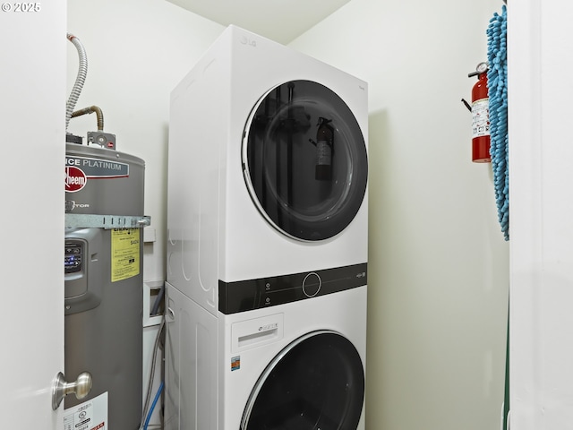 clothes washing area featuring water heater, laundry area, and stacked washer / dryer