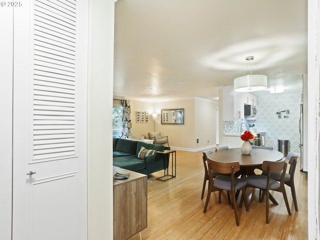 dining space featuring light wood-style floors and baseboards