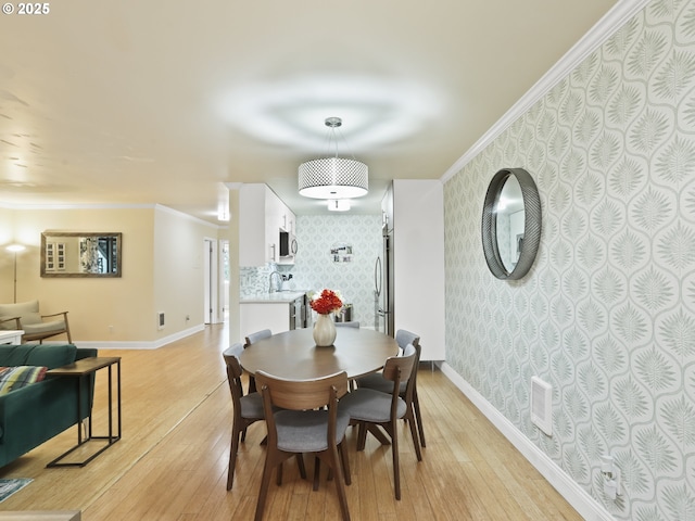 dining area with baseboards, ornamental molding, visible vents, and wallpapered walls