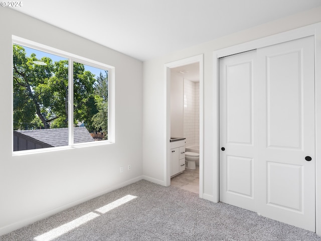 unfurnished bedroom with light carpet, a closet, and connected bathroom