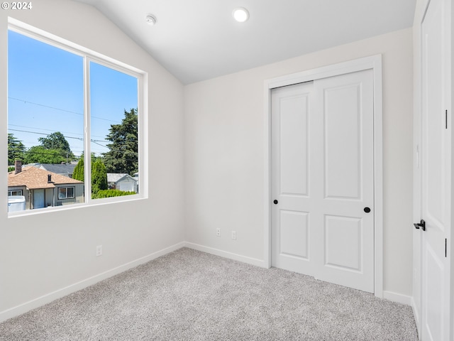 unfurnished bedroom featuring a closet, carpet, and lofted ceiling