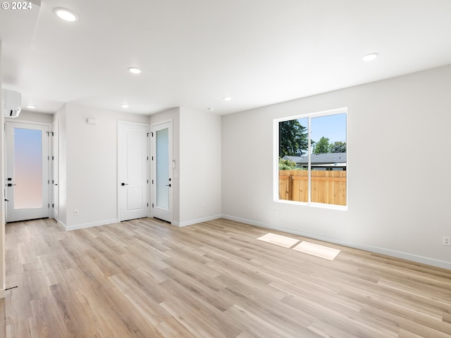 spare room with light hardwood / wood-style floors and an AC wall unit