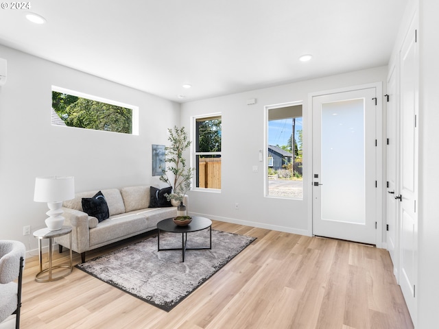 living room with light hardwood / wood-style floors and an AC wall unit