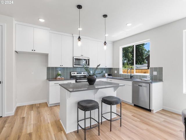 kitchen with white cabinets, appliances with stainless steel finishes, a center island, and light wood-type flooring