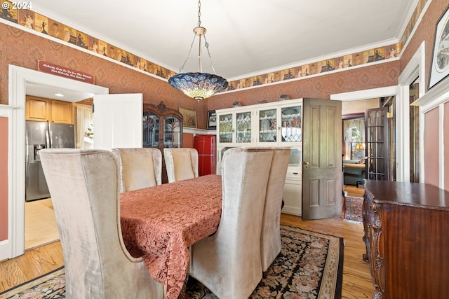 dining space with crown molding and light hardwood / wood-style flooring