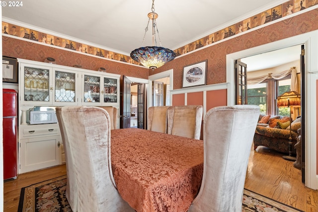 dining space with hardwood / wood-style flooring and crown molding