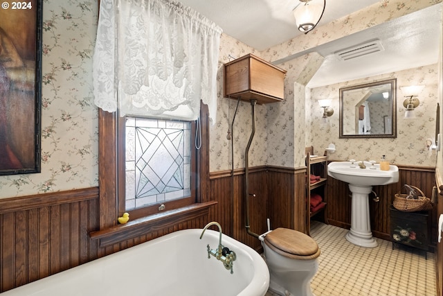 bathroom with tile patterned floors, a bathtub, and toilet