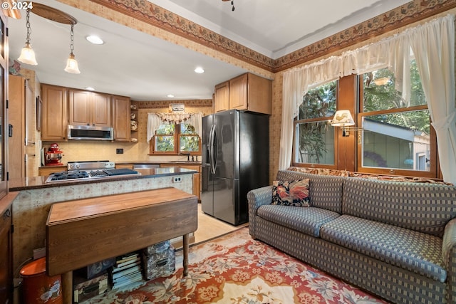 kitchen with appliances with stainless steel finishes, tasteful backsplash, sink, pendant lighting, and a notable chandelier